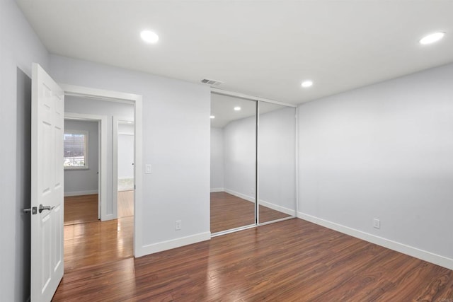 unfurnished bedroom featuring dark wood-type flooring and a closet