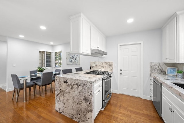 kitchen with light stone counters, backsplash, white cabinetry, and appliances with stainless steel finishes