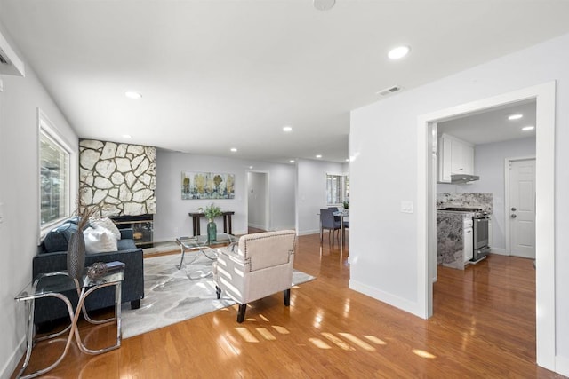 living room featuring light hardwood / wood-style flooring and a stone fireplace