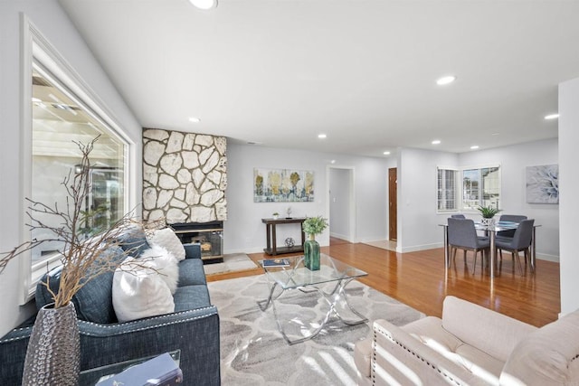 living room with light wood-type flooring and a stone fireplace