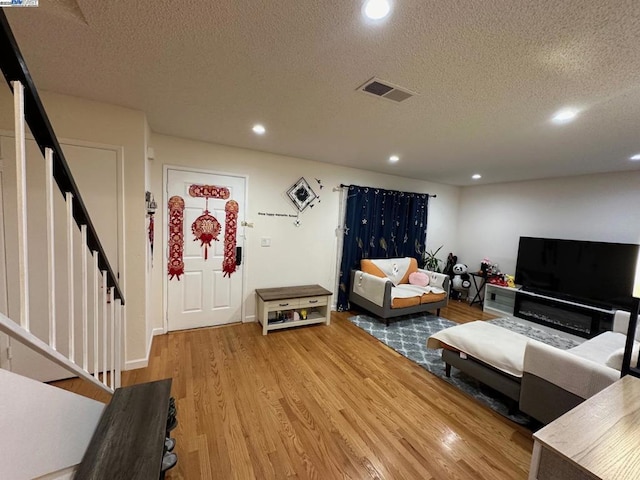 living room with a textured ceiling and light hardwood / wood-style flooring