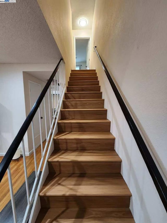 stairs featuring hardwood / wood-style floors and a textured ceiling