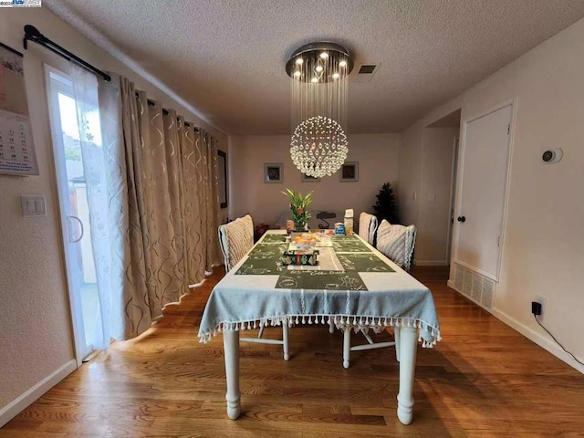 dining space featuring an inviting chandelier, hardwood / wood-style floors, and a textured ceiling