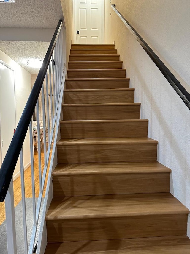 stairs with hardwood / wood-style floors and a textured ceiling