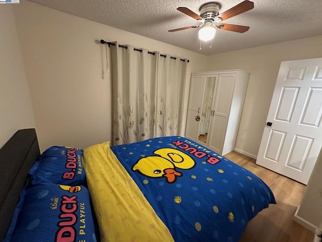 bedroom featuring ceiling fan, light hardwood / wood-style floors, and a textured ceiling