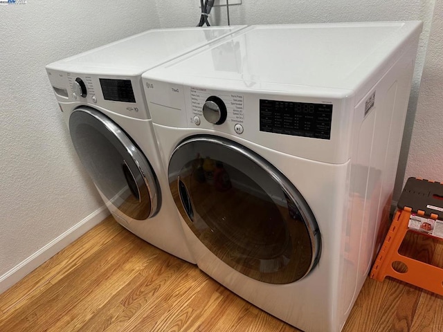 laundry area featuring washing machine and clothes dryer and light wood-type flooring