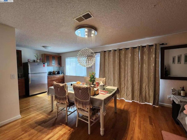 dining area with a textured ceiling, light hardwood / wood-style flooring, and a chandelier