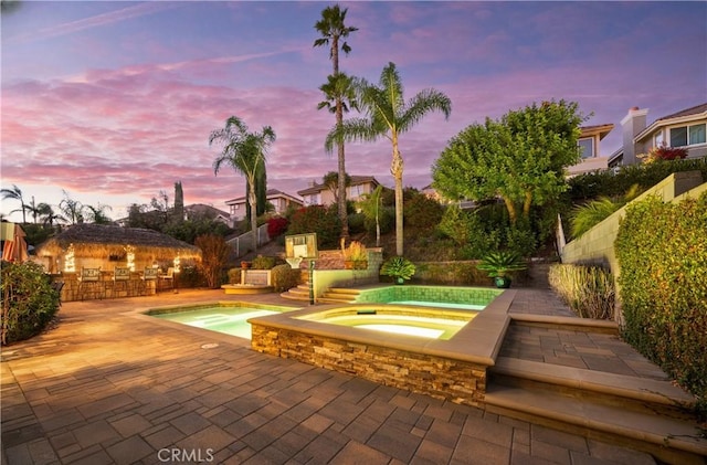 pool featuring a patio area, fence, and an in ground hot tub