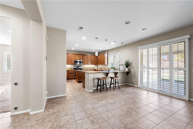 kitchen featuring hanging light fixtures, light tile patterned floors, kitchen peninsula, and a breakfast bar area