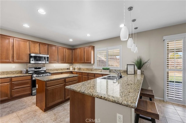 kitchen with kitchen peninsula, a breakfast bar area, stainless steel appliances, pendant lighting, and sink