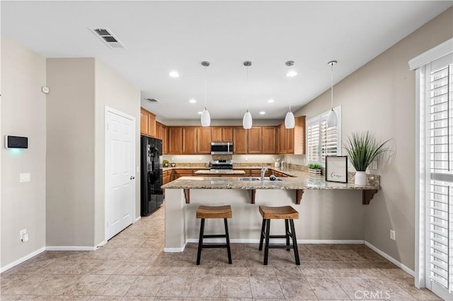 kitchen featuring pendant lighting, kitchen peninsula, stainless steel appliances, and a healthy amount of sunlight