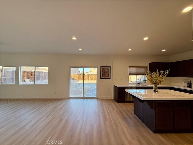 kitchen featuring dark brown cabinetry, dishwasher, light hardwood / wood-style floors, sink, and a breakfast bar