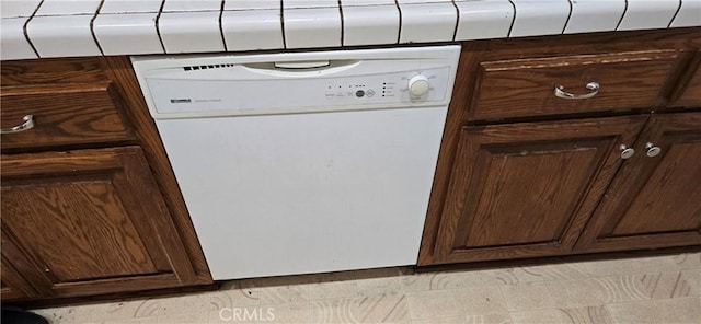 details with tile counters, white dishwasher, and dark brown cabinetry