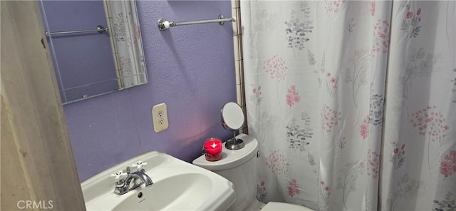 bathroom with toilet, sink, and a shower with shower curtain