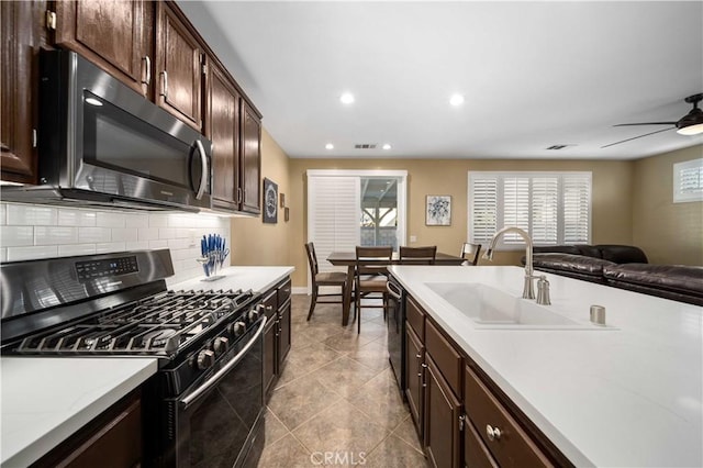 kitchen with ceiling fan, stainless steel appliances, decorative backsplash, dark brown cabinetry, and sink