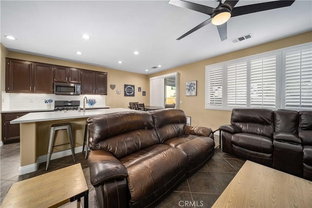 living room featuring ceiling fan, dark tile patterned flooring, and sink