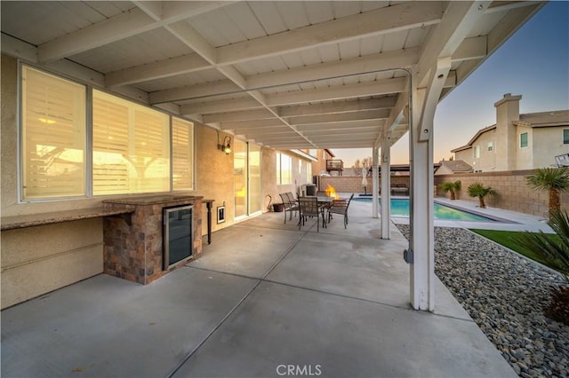 patio terrace at dusk featuring a fenced in pool