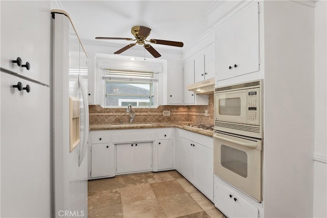 kitchen with white appliances, white cabinets, tasteful backsplash, sink, and ceiling fan