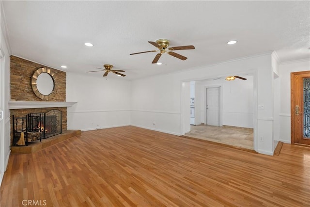 unfurnished living room with light wood-type flooring, a large fireplace, and crown molding