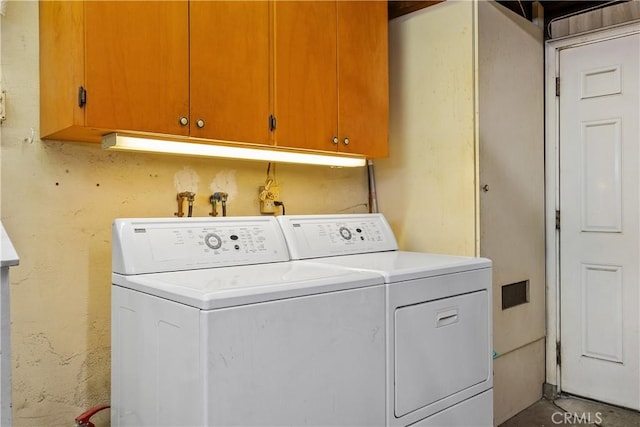 laundry room with washing machine and clothes dryer and cabinets