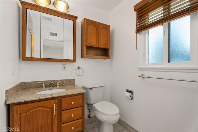 bathroom with toilet, vanity, and tile patterned floors