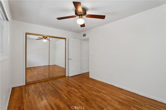 unfurnished bedroom featuring ceiling fan, a closet, and hardwood / wood-style floors