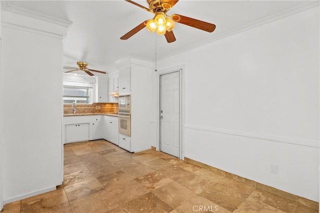 kitchen with built in microwave, oven, crown molding, white cabinets, and sink