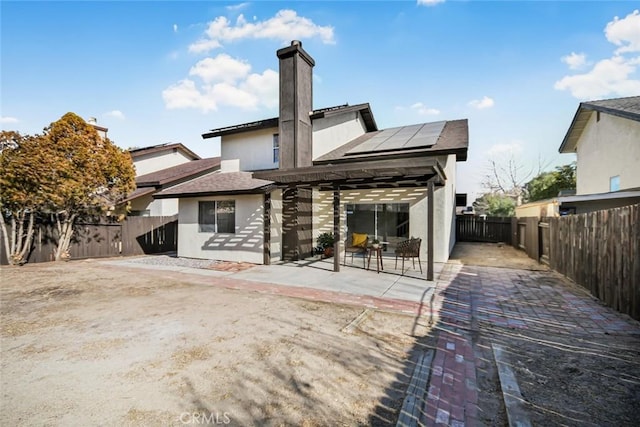 rear view of property with solar panels and a patio