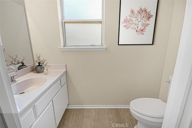 bathroom with toilet, hardwood / wood-style flooring, and vanity