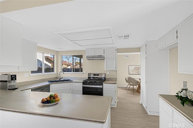 kitchen featuring light wood-type flooring, white cabinetry, gas stove, and sink