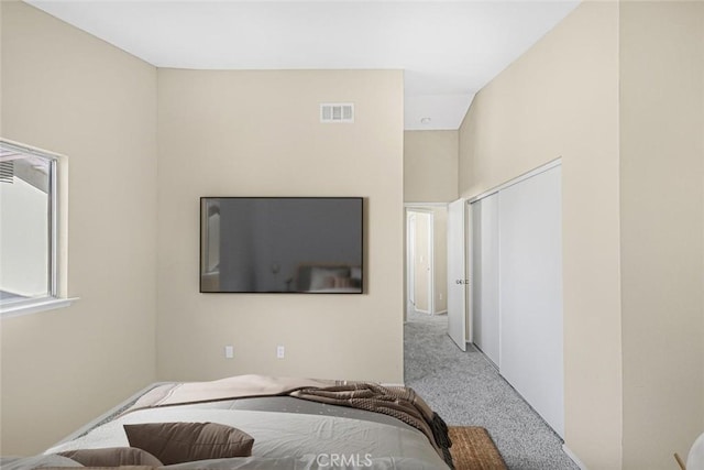 bedroom featuring vaulted ceiling, a closet, and light colored carpet