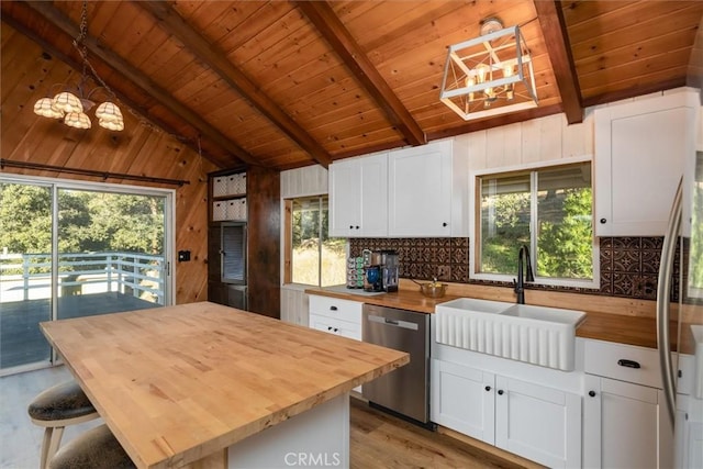 kitchen featuring white cabinets, wooden counters, stainless steel appliances, and pendant lighting