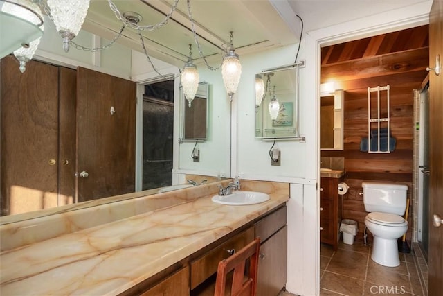 bathroom featuring toilet, tile patterned flooring, wood walls, and vanity