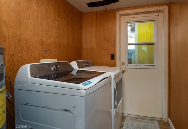 laundry area with washing machine and clothes dryer and wooden walls