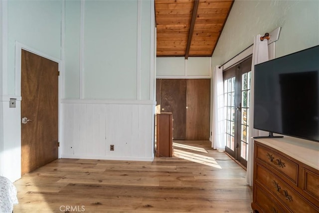 unfurnished living room with wood ceiling, french doors, vaulted ceiling with beams, wood walls, and light hardwood / wood-style flooring