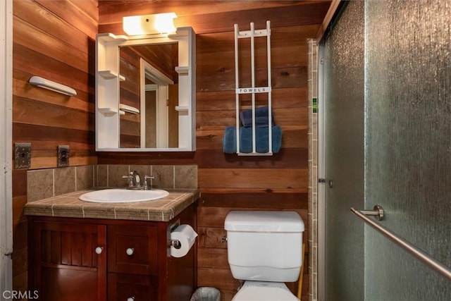 bathroom with toilet, vanity, and wood walls