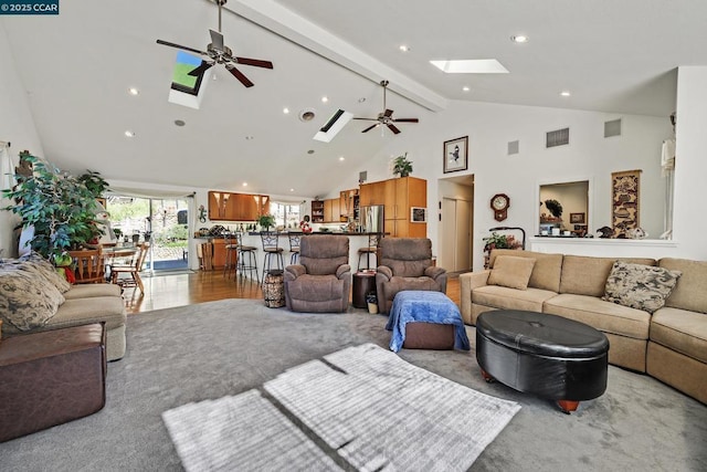 carpeted living room with ceiling fan, a skylight, beamed ceiling, and high vaulted ceiling