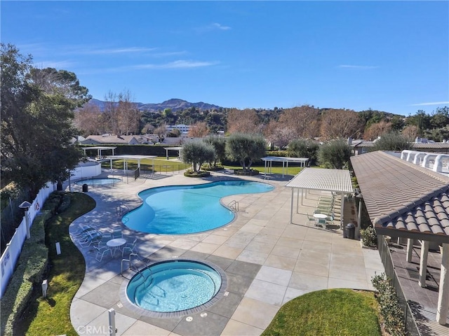 view of swimming pool with a patio, a mountain view, and a community hot tub