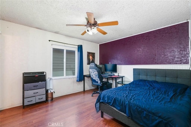 bedroom with a textured ceiling, ceiling fan, and wood-type flooring