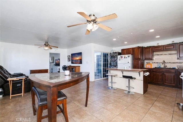 dining room with stacked washing maching and dryer, ceiling fan, light tile patterned floors, and sink