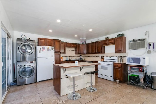 kitchen with white appliances, a kitchen island, a kitchen bar, decorative backsplash, and stacked washer and clothes dryer