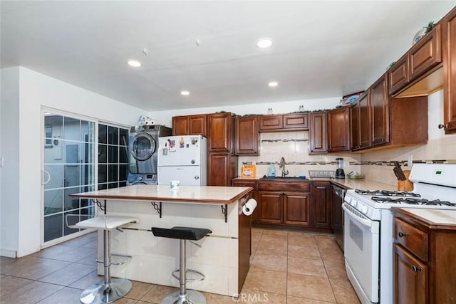 kitchen featuring white appliances, a breakfast bar area, stacked washer and dryer, and a kitchen island