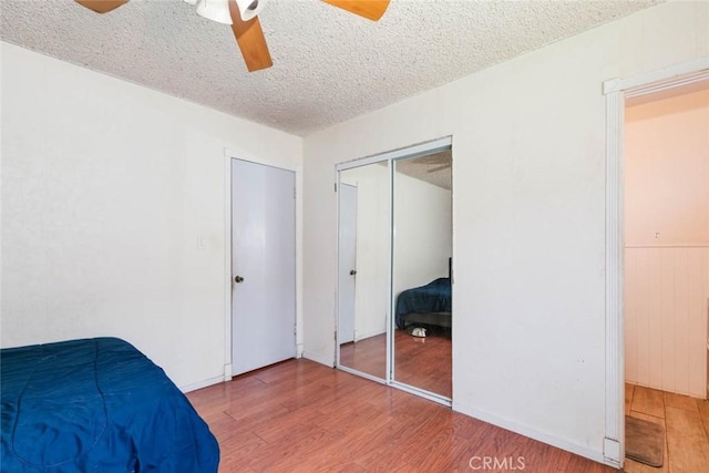 bedroom featuring ceiling fan, a textured ceiling, a closet, and hardwood / wood-style floors