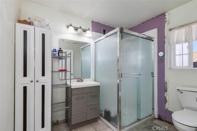 bathroom with a shower with door, toilet, vanity, and tile patterned flooring