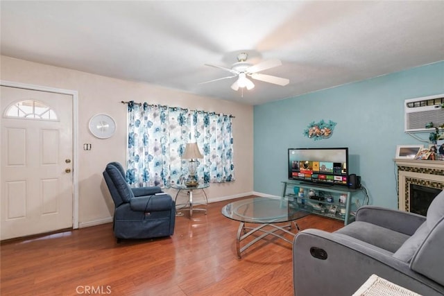 living room with ceiling fan, a wall mounted air conditioner, a premium fireplace, and hardwood / wood-style floors