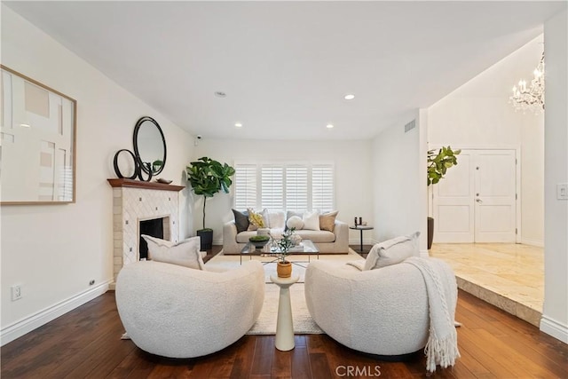 living room featuring hardwood / wood-style flooring, a tile fireplace, and a chandelier