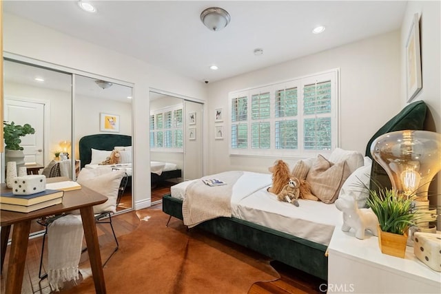 bedroom with hardwood / wood-style floors and multiple closets