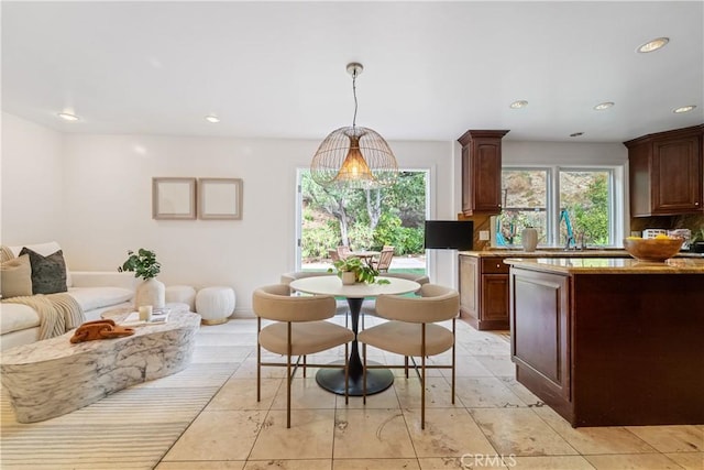 kitchen with dark brown cabinets, backsplash, and hanging light fixtures