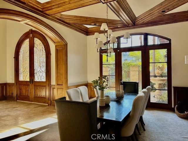 carpeted dining area with crown molding, french doors, beam ceiling, coffered ceiling, and a chandelier