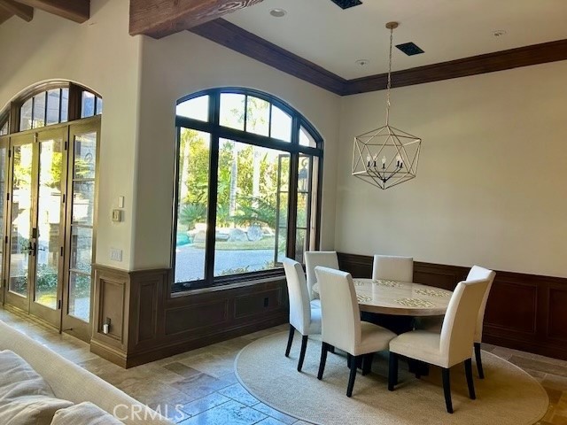 dining area featuring plenty of natural light, beamed ceiling, and an inviting chandelier